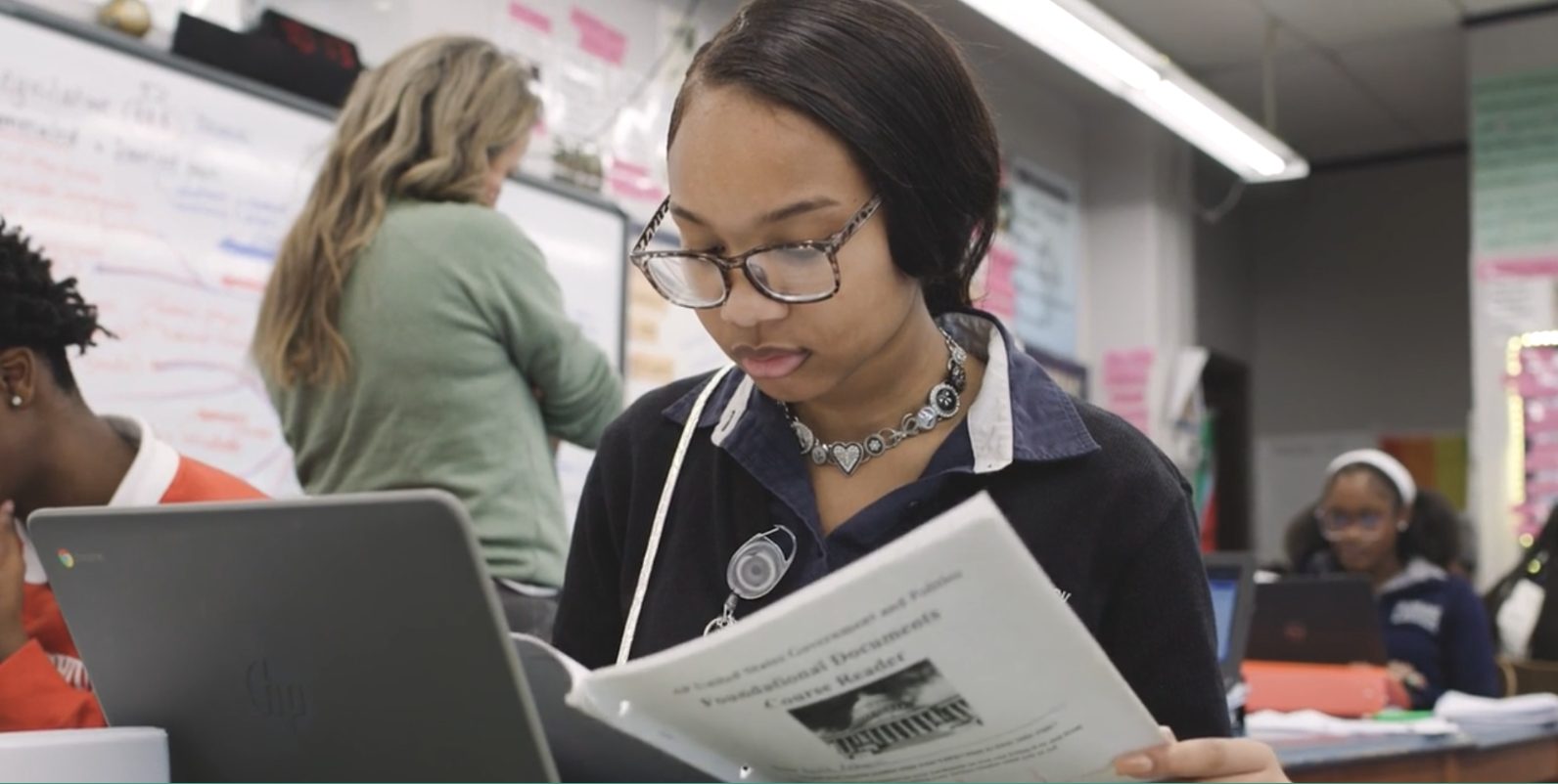 A New Orleans student reads a U.S. Government course reader during class